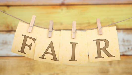 Four squares of paper spelling FAIR pegged to line. Yellow background. 