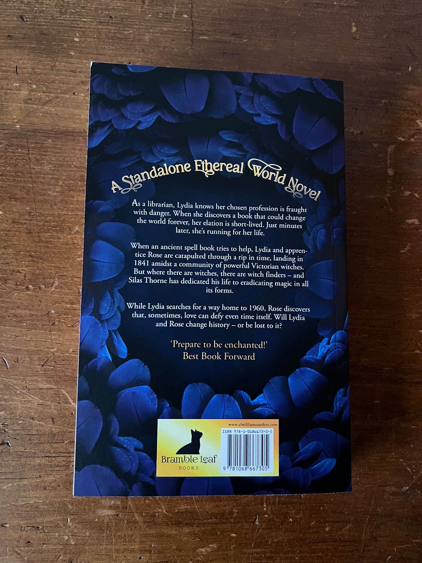 Back cover of a book with blue floral design and text on a wooden surface