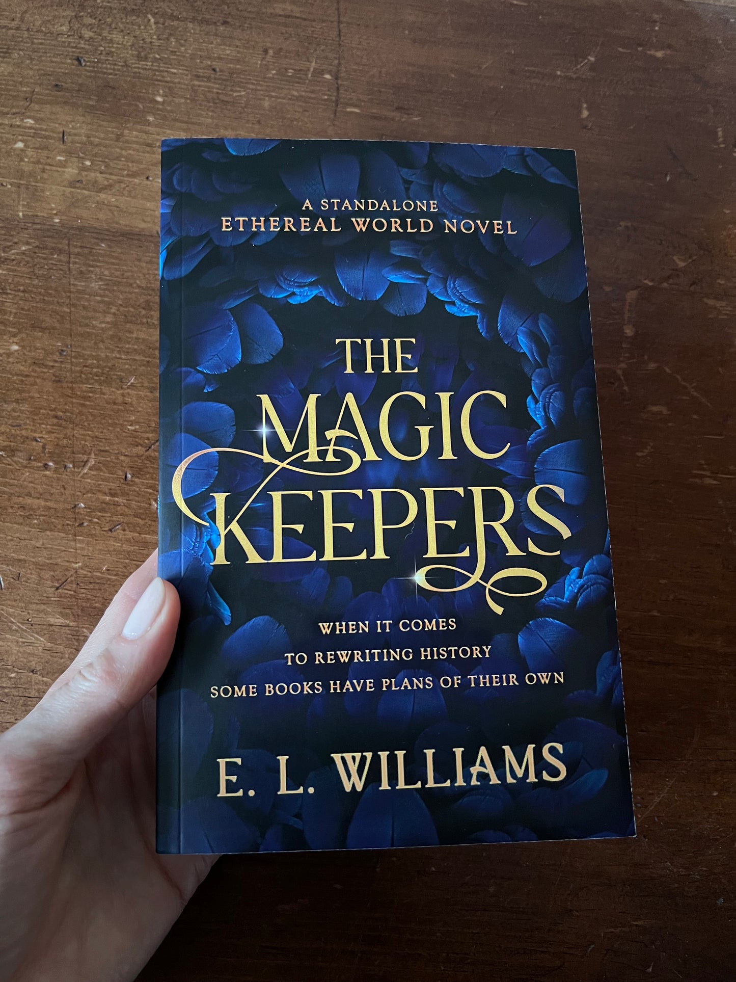 Book titled 'The Magic Keepers' by E.L. Williams held on a wooden surface