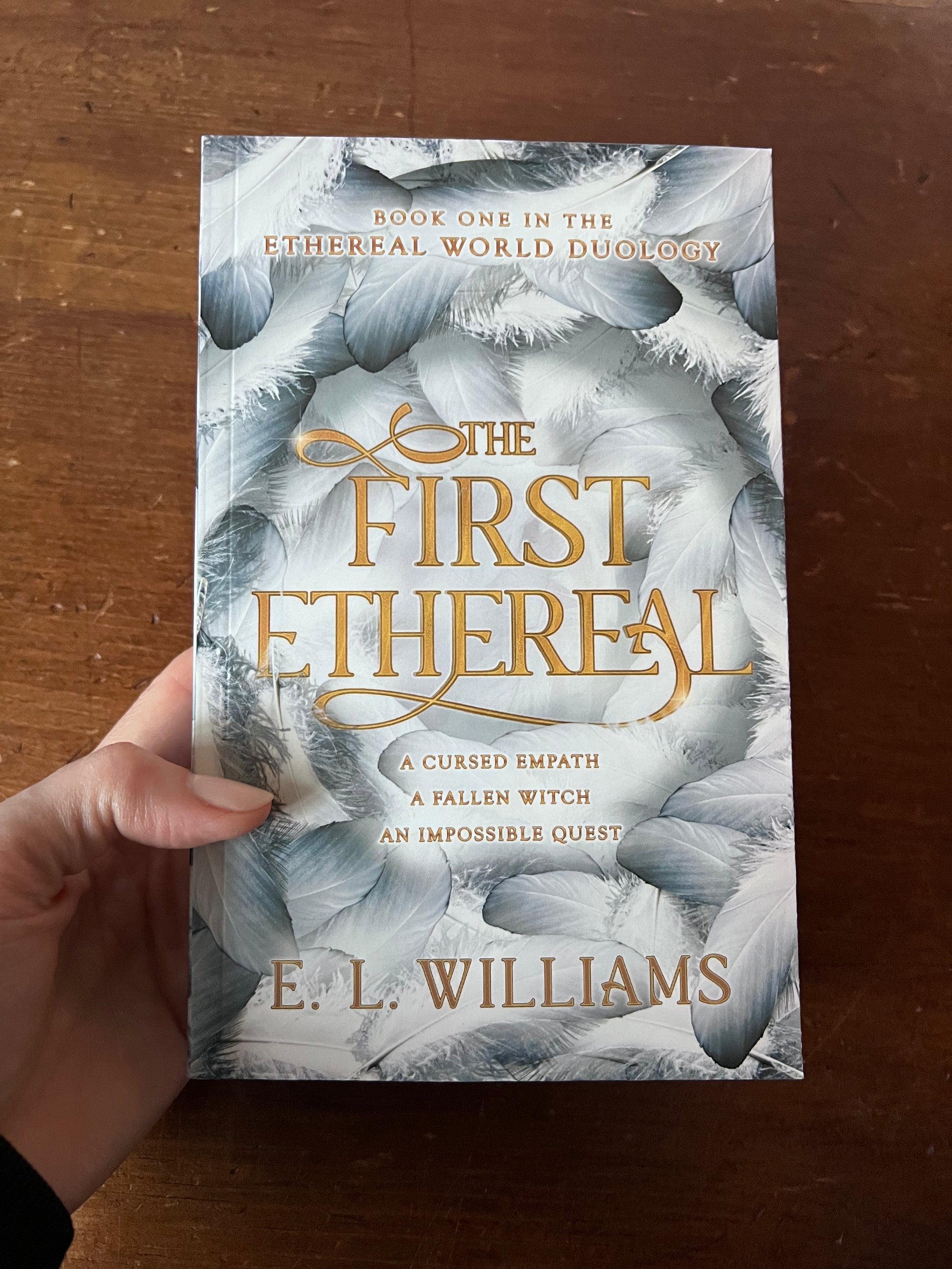 Book titled 'The First Ethereal' by E.L. Williams held against a wooden background